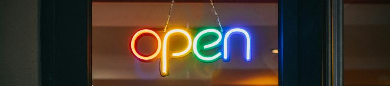 Coloured neon open sign in shop door. Photo by Viktor Forgacs via Unsplash